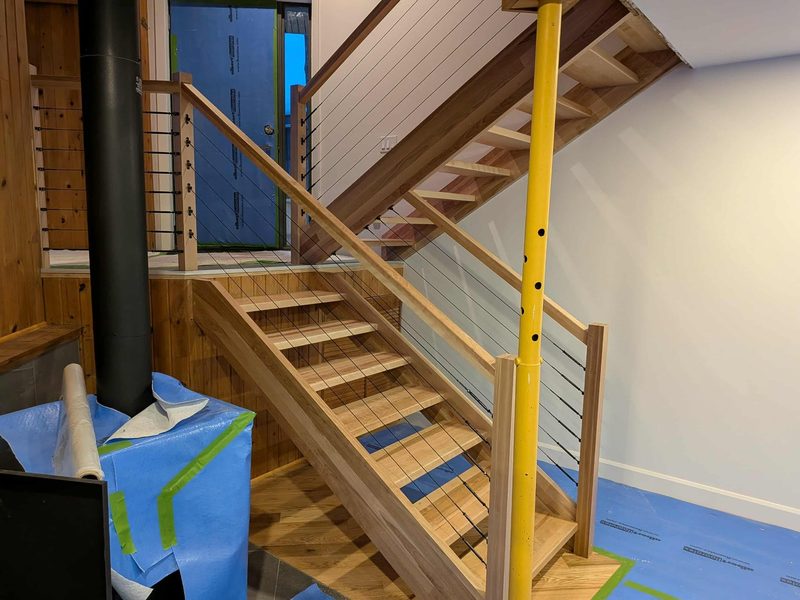 Escalier flottant en merisier avec garde-corps à câbles d'acier dans un chalet