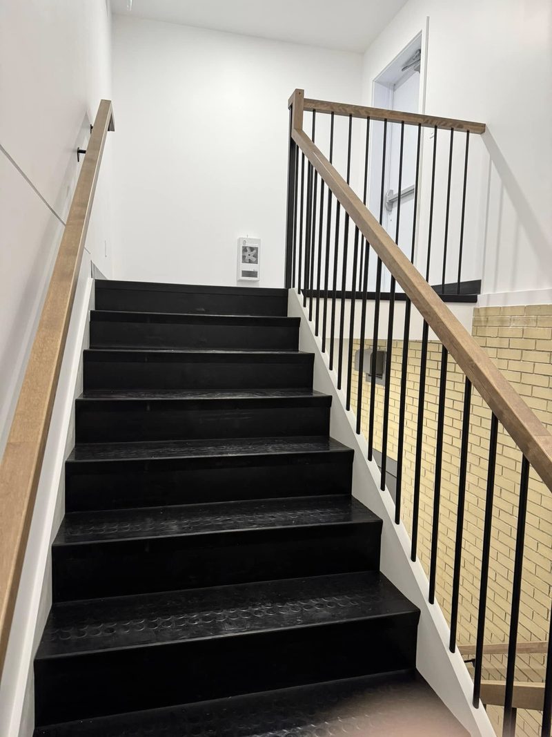 Départ d'escalier commercial avec garde-corps à barreaux noirs