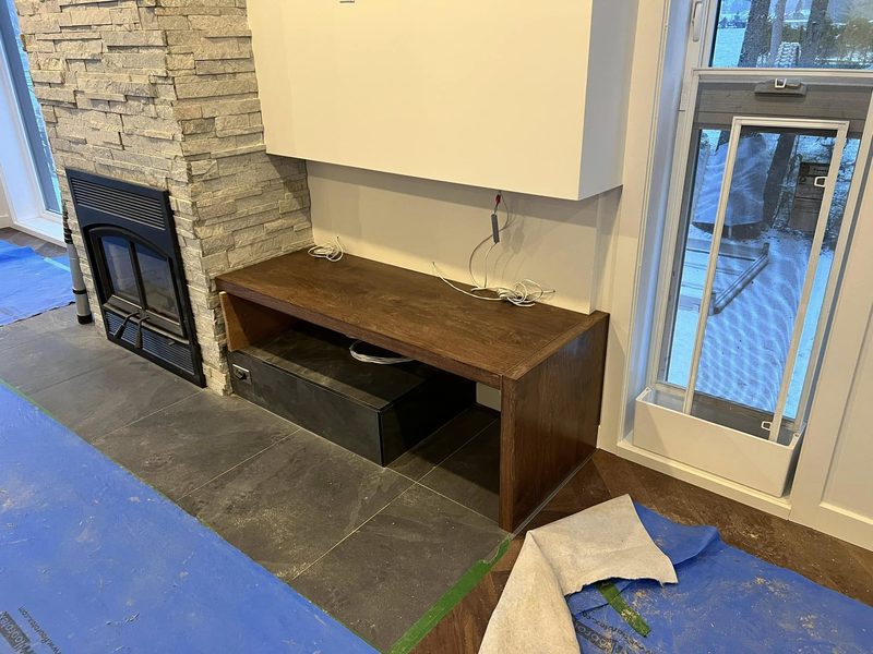 Détail d'un meuble en bois foncé intégré au mur du foyer