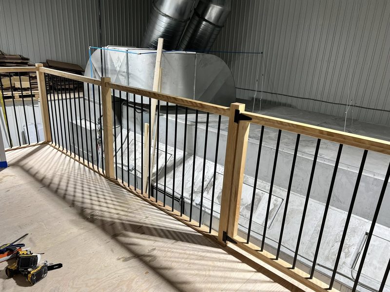 Garde-corps de mezzanine en bois et barreaux noirs dans un bâtiment industriel