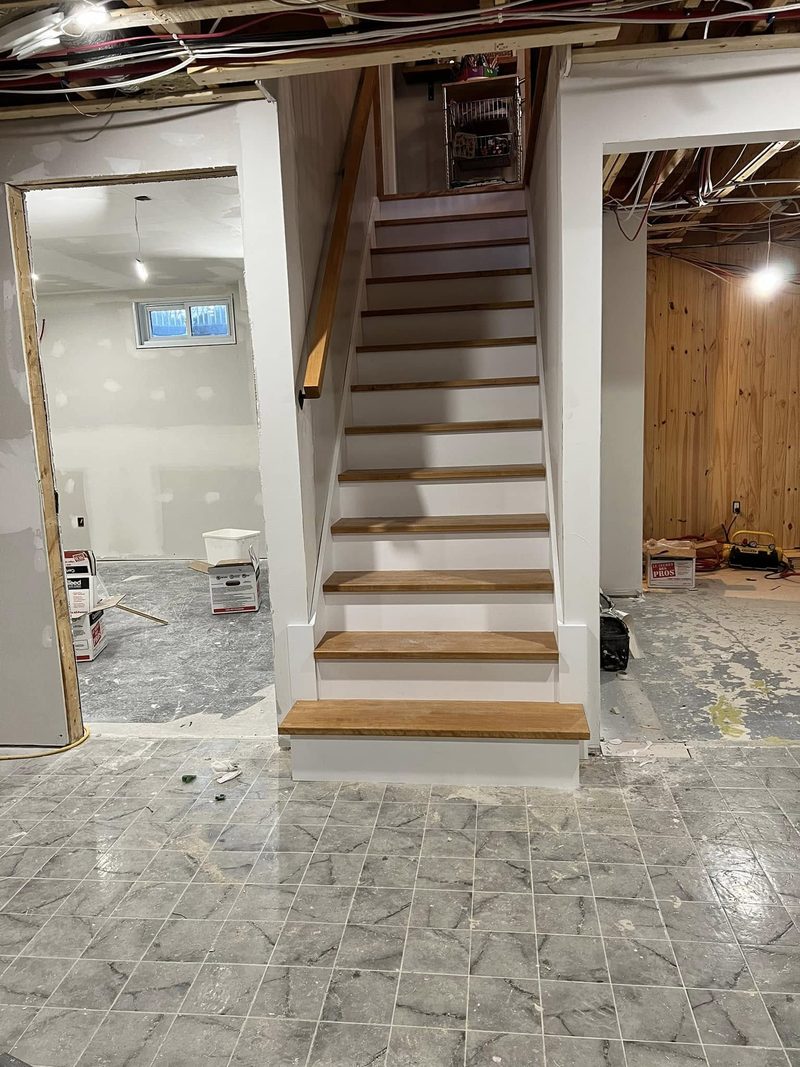 Escalier droit en bois avec contremarches blanches dans un sous-sol en construction