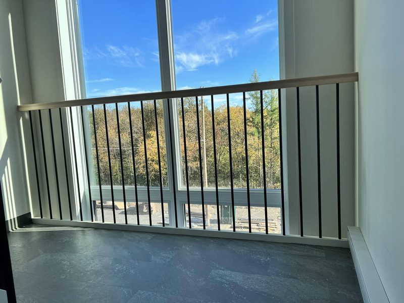 Garde-corps à barreaux noirs devant une fenestration pleine hauteur