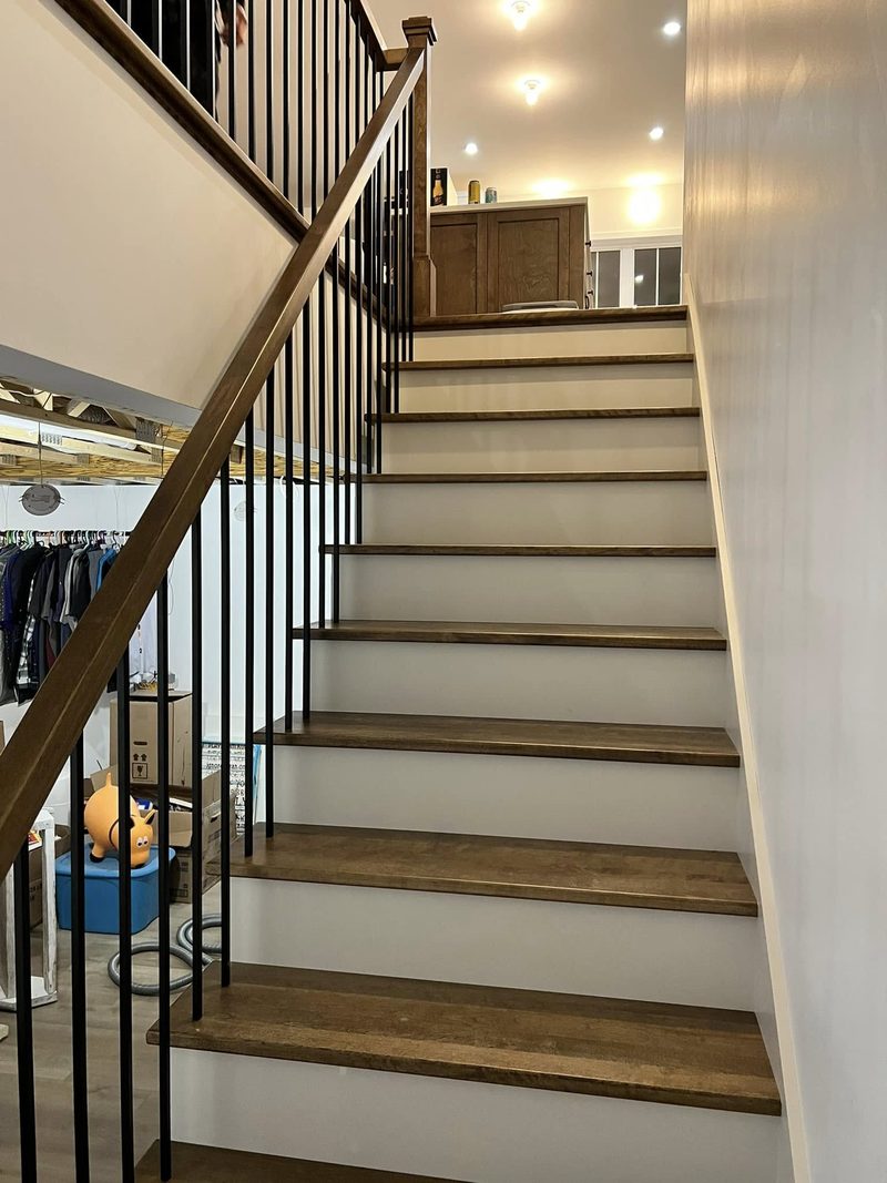 Escalier droit en bois avec contremarches blanches et garde-corps à barreaux noirs