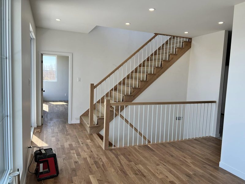 Escalier en bois clair avec garde-corps de palier à barreaux blancs