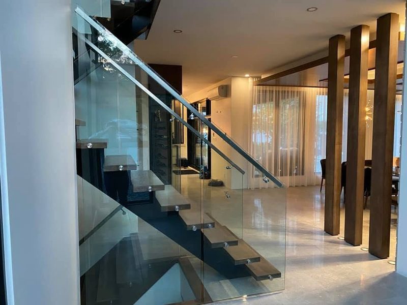 Escalier flottant avec garde-corps de verre et colonnes décoratives en bois