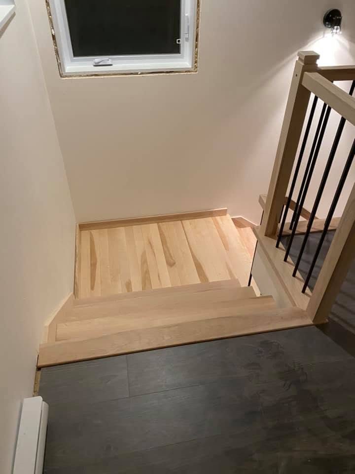 Palier d'escalier en bois clair sous une fenêtre de toit