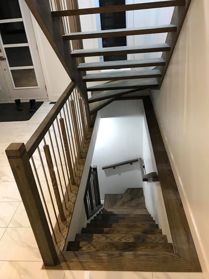 Escalier en bois foncé avec garde-corps, vu de l'étage