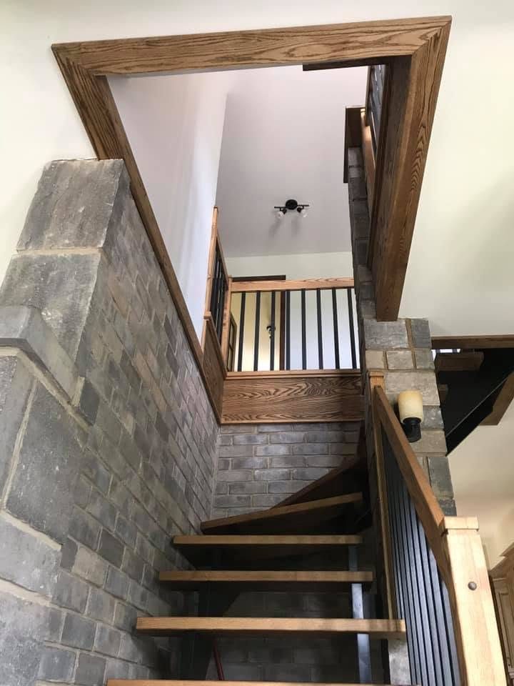 Escalier flottant entre des murs de pierre, vu de l'étage